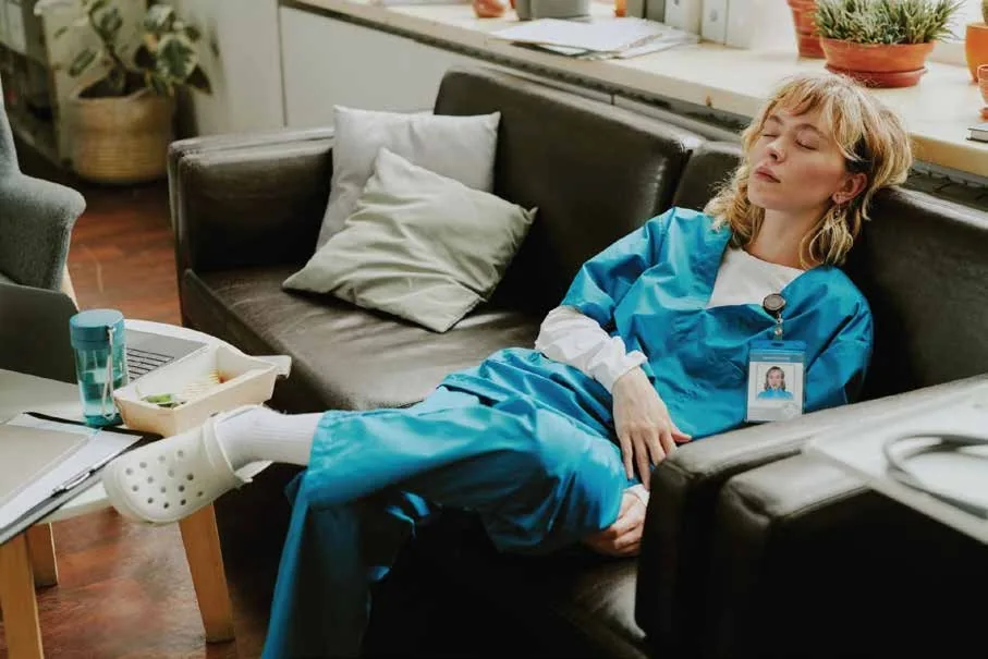 Exhausted healthcare worker resting during a break after a long hospital shift, highlighting the effects of nurse fatigue and staffing shortages