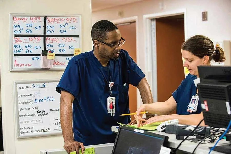 Hospital nurses reviewing patient care information and coordinating treatment at the nurses' station